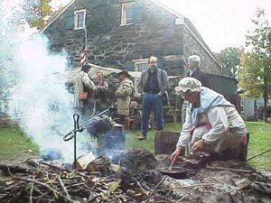 Member Nancy Conod is shown making hot chocolate over the fire